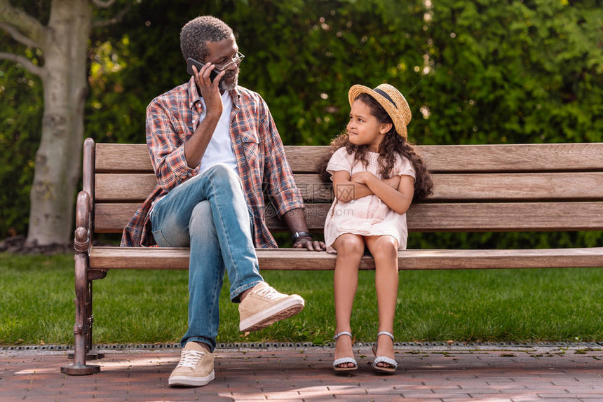 非洲裔美国人的孙女交叉双臂看着她的祖父在公园里用图片
