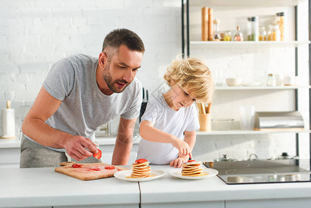 专注的小男孩和父亲在厨房的煎图片