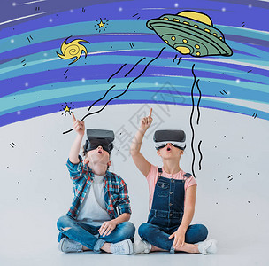 临时儿童在坐地板上时使用虚拟现实头耳机图片