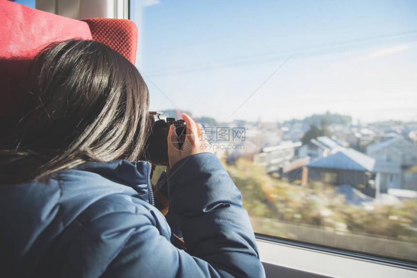 乘火车旅行时使用数码相机在窗外拍照的亚洲女孩图片