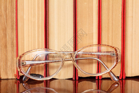 木制架上的眼镜和许多硬书教育背景图书图片