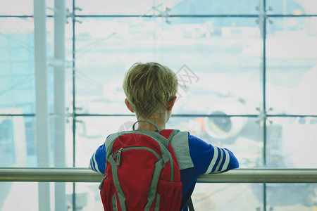 小男孩看着机场的飞机旅行概念图片