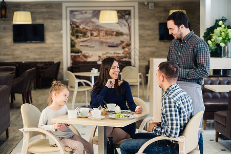 家庭父母身份技术人的概念快乐的母亲父亲和小女孩吃晚饭让服务员用图片