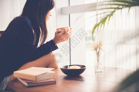 年轻女子喝茶望着窗外图片