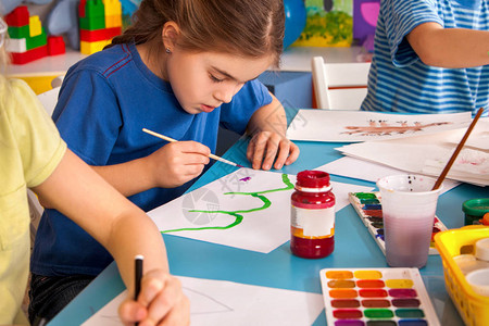 小学生在艺术学校课上画孩子在桌子上用颜料画幼儿园里的男孩和女孩绘画教育培养孩子的创造能力背景图片