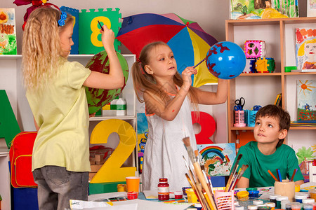 小学生在艺术学校课上画儿童男孩和女孩在幼儿园用气球上的颜料画他们学会在团队中生活儿童创造力中背景图片