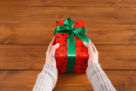 DIY爱好女人的手用绿丝带用红纸给包裹的圣诞假期手工制作的礼物礼物盒图片