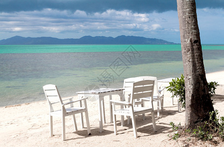 沙滩上的白色桌子面朝大海图片