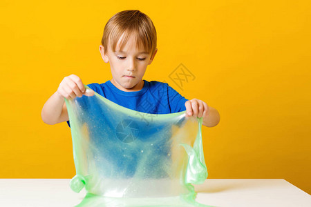 孩子玩粘液快乐的男孩在餐桌上制作粘液自制流行玩具史莱姆有图片