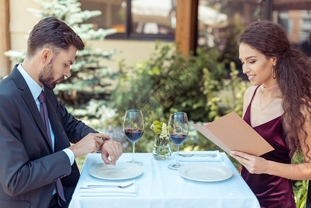 在餐厅有浪漫约会的情侣女人在菜单中选择晚餐图片