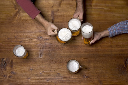 三个人在酒吧的木桌上喝啤酒图片