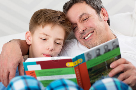 父亲和儿子在读一本书小心爸帮助孩图片