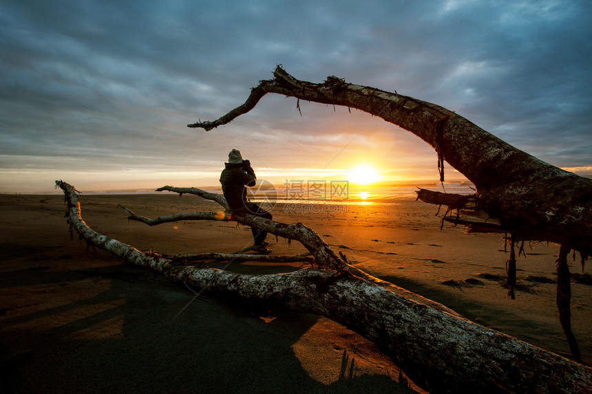 摄影师和日落在黑沙滩Hokitika图片