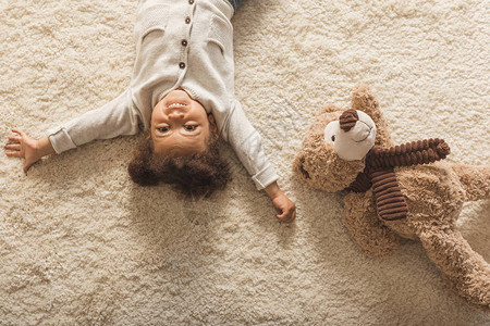 可爱的非洲裔美国小女孩躺在家里的地毯上的俯视图图片