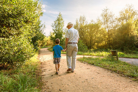 带着帽子和孙子走在自然之路上图片