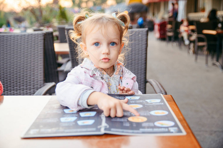 坐在咖啡馆的小女孩从菜单式生活方图片