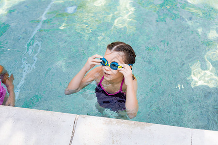 游泳池中女孩在望远时触摸游泳护目镜图片