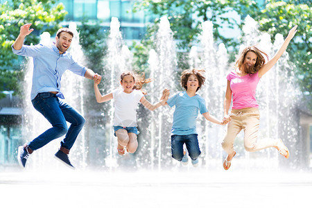 快乐的年轻家庭有小孩在公园跳户外露天图片