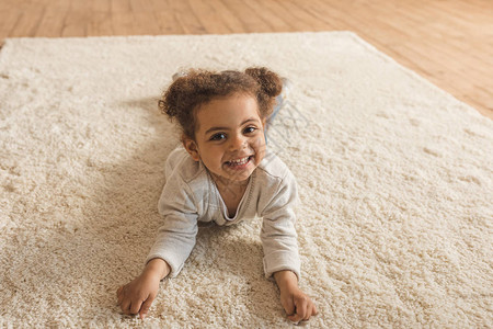 可爱的非洲小女孩躺在家里地毯上的美图片