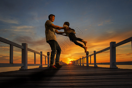 父亲和女儿一起在海滩上玩耍日落时图片