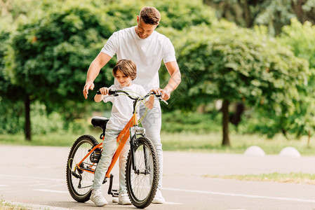 父亲和儿子在路上看脚踏车图片