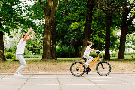 一边是快乐的父亲在孩子骑自行车时为儿图片