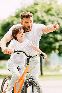 父亲和儿子在孩子骑自行车时向前看爸图片