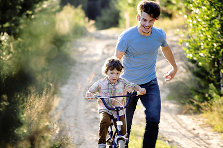 父亲在外边学儿子骑自行车背景图片