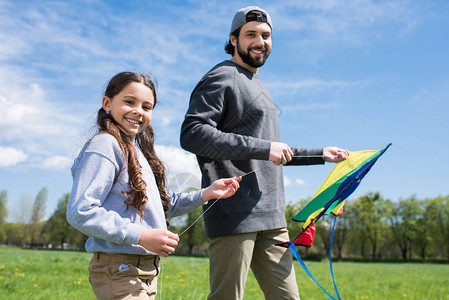 女儿和父亲在公园草地上放风筝图片
