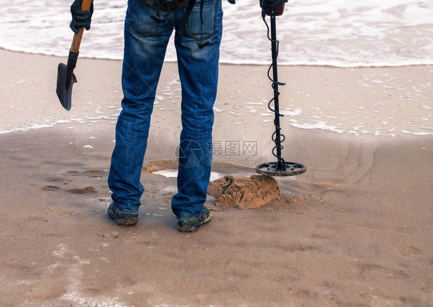 男子使用金属探测器在沙滩上寻找金属或丢失的宝藏他图片