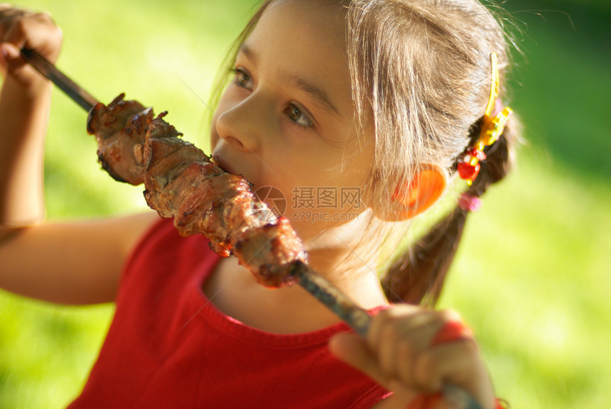 快乐的小女孩吃烤羊肉串图片
