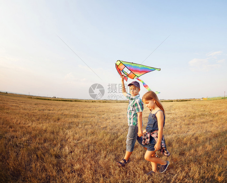 快乐的男孩和小女孩在阳光明媚的夜晚在草地上带图片