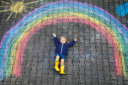 快乐的蹒跚学步的小女孩穿着橡胶靴图片
