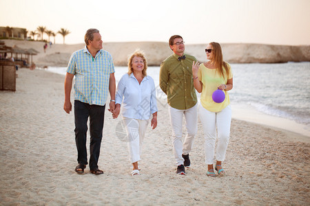快乐的老年夫妇和年轻夫妇在海边散步父母和成年子女图片