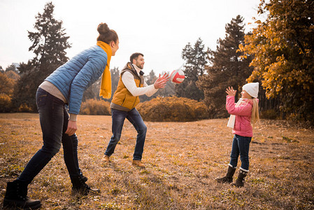 在秋季公园玩球的幸福家庭图片