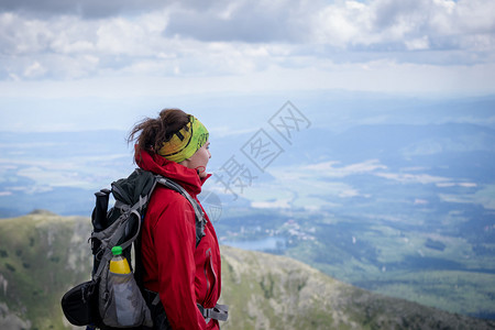 年轻女登山者在艰难的山顶后享受着山区景色图片