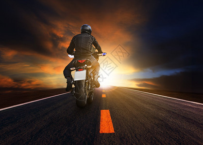 在沥青高速公路上骑大摩托车的青年男子图片