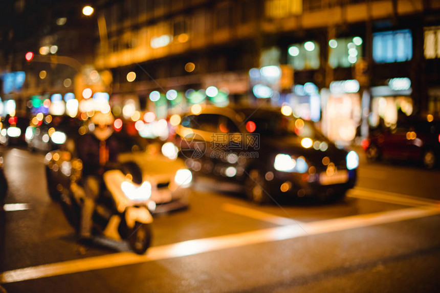 汽车和摩托车在夜间拥挤的城市的路口等待绿灯时被图片