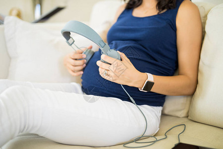 孕妇在沙发上为胎儿演奏音乐图片