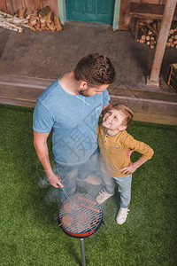 父亲和儿子在烧烤时做牛肉汉堡和热狗香图片