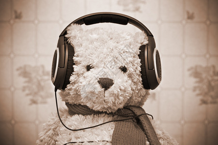 泰迪熊在耳机上监听音乐照片由SepiaToned图片