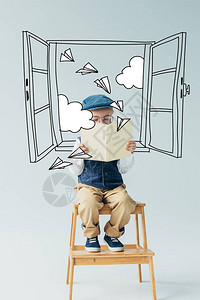坐在木制楼梯和灰色背景读书的可爱孩子图片