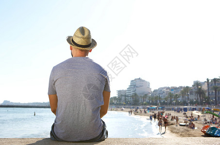 夏天一个人坐在海滩上看着沙滩的男图片