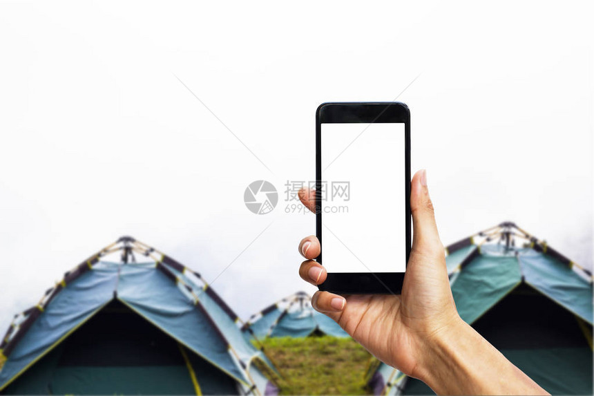手持黑色智能手机与白色屏幕在露营帐图片