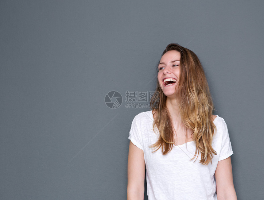 一位快乐的年轻女子在灰色背景下欢笑而喜悦图片