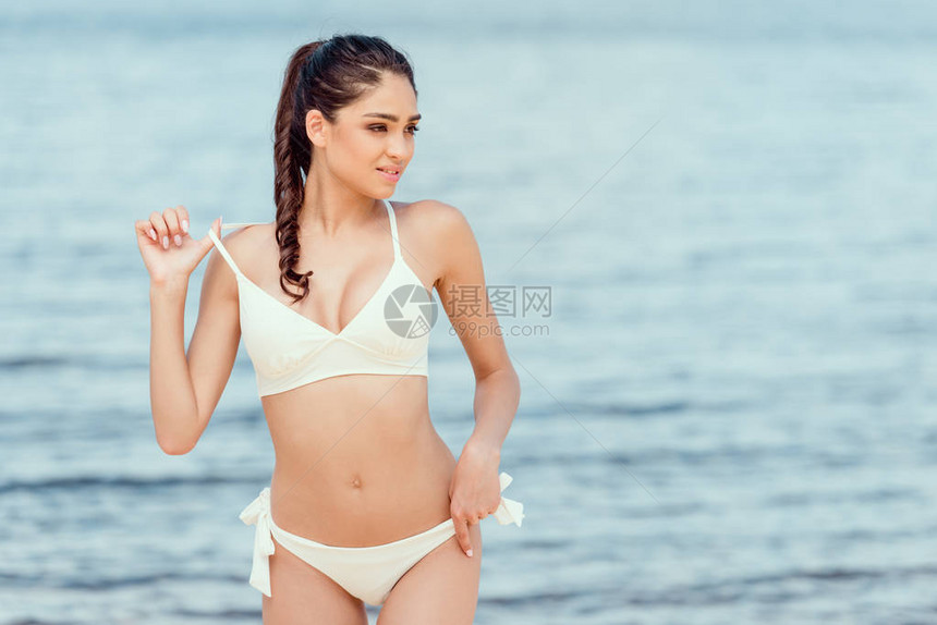 穿着白泳衣在海边滩上摆着的图片