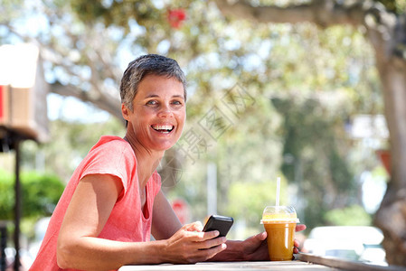 带着手机和饮料坐在外边的微笑着的老图片