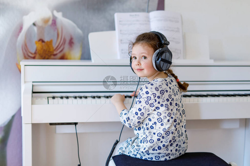 漂亮的小女孩在或音乐学校用耳机弹钢琴学龄前儿童学习演奏乐器很开心教图片