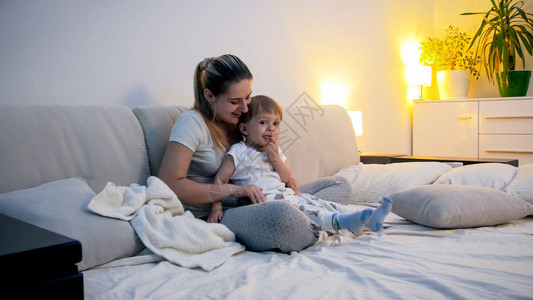 美丽的女人和她的小孩儿子一起坐在床图片