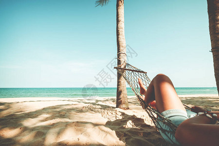 夏季休闲感女美丽晒黑的腿在热带沙滩的吊床上放松图片